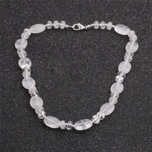 Gros plan de perles en quartz translucide et fermoir mousqueton sur fond noir scintillant