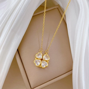 Detail of gold four-leaf clover pendant made of four heart-shaped crystals on satin