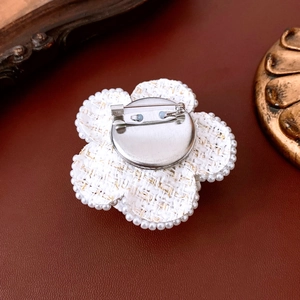 Detail view showing the metal base and silver safety pin back of the tweed flower brooch