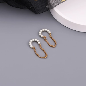 Close-up of gold-plated pearl hoop earrings with elegant long hanging metal tassels