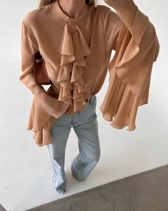 Detail of layered ruffle trim and triple flared sleeves on an apricot chiffon shirt