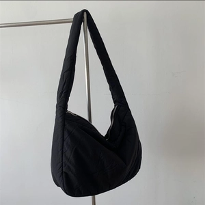 Detail of black quilted nylon crescent bag with wide shoulder strap and zip closure