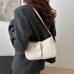 Close-up of cream underarm bag featuring lychee texture and golden D-buckle on a blazer