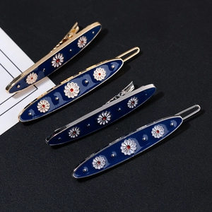 Detailed view of four dark blue enamel hair clips with floral patterns and metal base