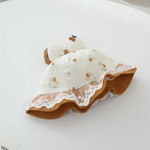 Detail of baby sun hat featuring fruit print, large bow and white lace floral trim