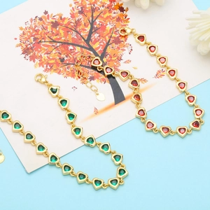 Detail view of heart-shaped zircon bracelets in gold with green and red faceted stones