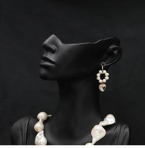 Detailed close-up of natural pearl earrings with gold heart-shaped diamond drops