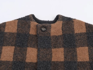 Detailed view of brown and grey plaid knit cardigan with a black button and soft texture