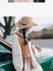Outdoor shot of a brown suede tassel vest paired with a white hollow-out dress and straw hat