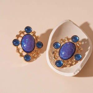 French vintage gold earrings with purple oval stones and blue crystals on beige background