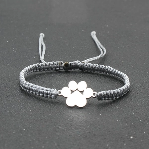 Detail view of a handmade gray braided cord bracelet with a silver dog paw charm