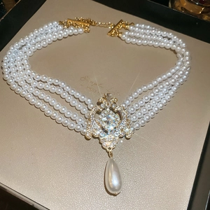 Détail d'un collier de perles multicouche avec pendentif doré dans son coffret cadeau