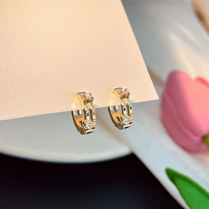 Vue macro de boucles d'oreilles cœur dorées géométriques avec strass pavés