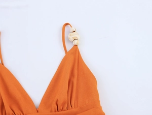 Détail de la robe orange à col en V avec perle de marbre et tissu en lin texturé