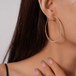 Close-up of gold hoop clip-on earring with sparkling diamonds on a female model