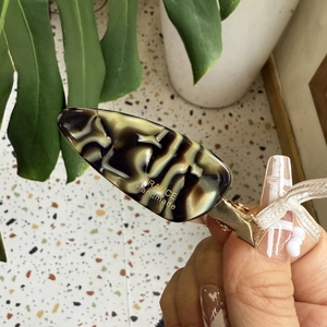 Close-up of tortoise shell acetate hair clip with gold metal base and handmade logo