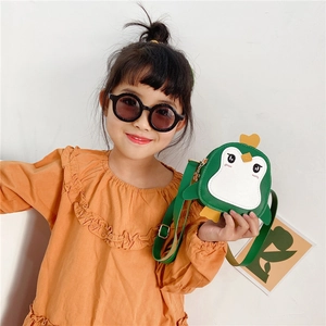 Close-up of green penguin cartoon crossbody bag with adjustable strap on young model