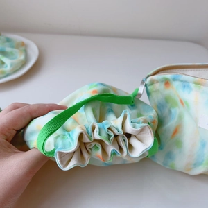 Detail of mint green watercolor tie-dye fabric pouch set with drawstring and zipper closure