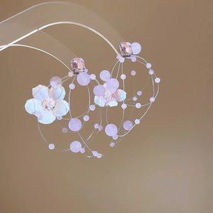Detail of pink crystal earrings with white fabric flowers and beaded tassels