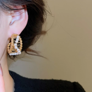 Detailed shot of 18k gold plated C-shaped hollow earrings with woven metal and white pearls