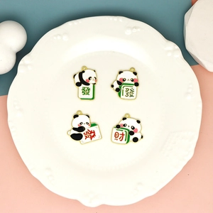 Détail de quatre pendentifs panda mahjong en émail allié sur une assiette décorative