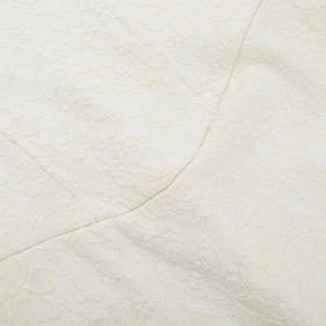 Nahaufnahme der filigranen weißen Spitzenstickerei und des Hohlmusters am Langarmkleid