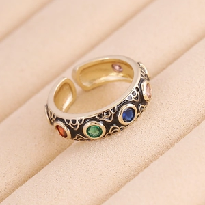 Macro shot of gold-plated ring featuring multi-colored gemstones and intricate cutout details