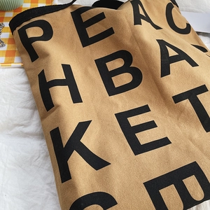 Close-up of khaki canvas tote bag featuring bold black lettering and fabric texture