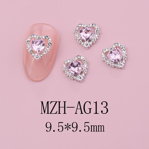 Detail of pink heart-shaped nail gems with silver frame and white crystals on pink nails