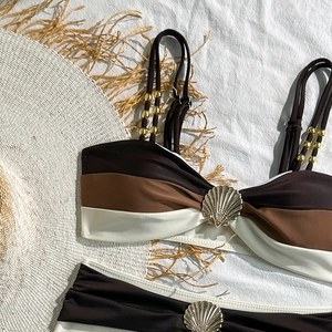 Close-up of golden shell buckle and beaded straps on a three-color bikini set