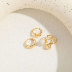 Detail view of gold ring set featuring pearl accents and geometric star textures