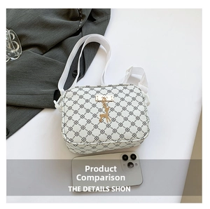 Detail of white crossbody bag featuring black geometric patterns and gold deer charm