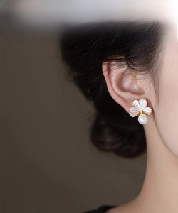 Gros plan de boucles d'oreilles fleurs et perles portées par un mannequin sous lumière douce