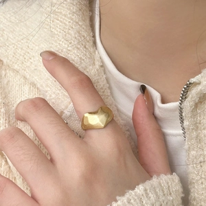 Macro detail of gold irregular ring with matte brushed finish worn on finger