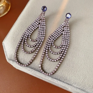 Detail of layered purple teardrop fringe earrings with sparkling crystals on velvet