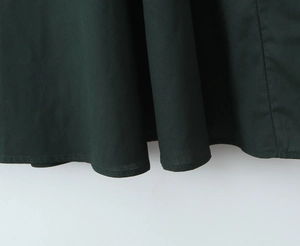 Detailed close-up showing the hem stitching and texture of dark green woven fabric