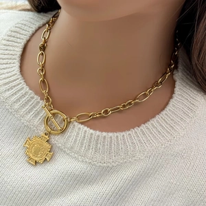 Close-up of gold plated OT buckle chain necklace with vintage crest medallion pendant