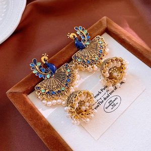 Macro detail of vintage peacock earrings with blue enamel and white pearl tassels