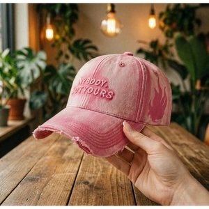 Detail of pink washed cotton baseball cap with vintage embroidery and frayed brim