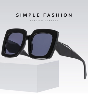 Detail view of stylish large square sunglasses featuring a thick frame and dark grey lenses