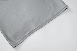 Détail de l'ourlet d'une robe grise montrant la couture double aiguille et le tissu lisse