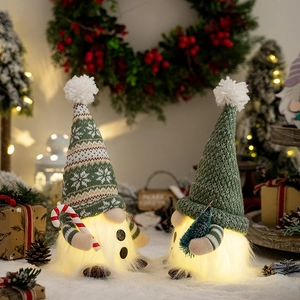 Close-up of glowing Christmas gnomes with knitted hats and warm LED lights decor