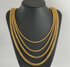 Detailed layered view of four gold wheat necklaces in different lengths on a black bust
