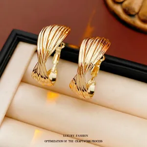 Minimalist twisted gold hoop earrings with polished texture in a beige velvet jewelry box