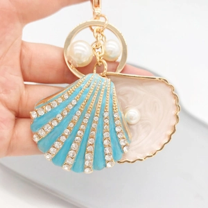 Detailed view of blue enamel seashell keychain with sparkling rhinestones and pearls