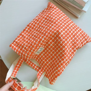 Detailed top view of orange geometric pattern canvas tote bag with textile brand label