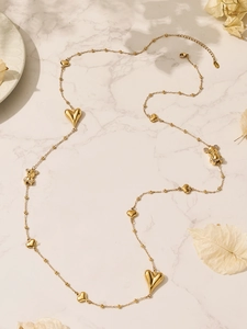 Detailweergave van lange gouden ketting met gepolijste harten en CZ-beertjes