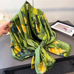 Detail of silk-like long scarf with vibrant yellow lotus floral print on light green fabric