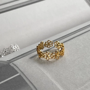 Macro detail of golden open ring featuring intricate hollow floral design patterns