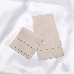 Detail of beige microfiber suede jewelry pouches on white silk fabric background